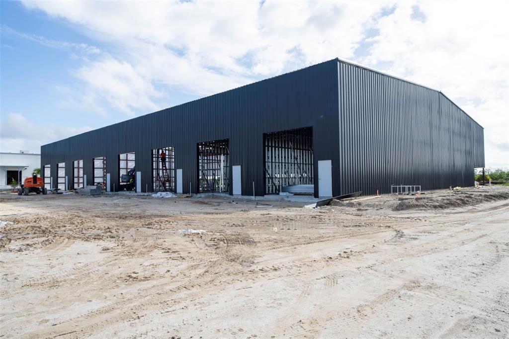 A large, dark-sided industrial warehouse building under construction on a dirt lot — 8411-8419 DUFFIE DRIVE, PUNTA GORDA, FL