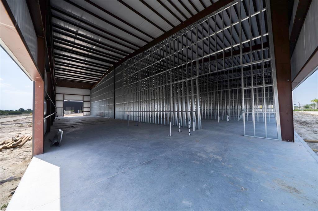 An unfinished warehouse interior features exposed metal framing, a concrete floor, and high ceilings — 8411-8419 DUFFIE DRIVE, PUNTA GORDA, FL