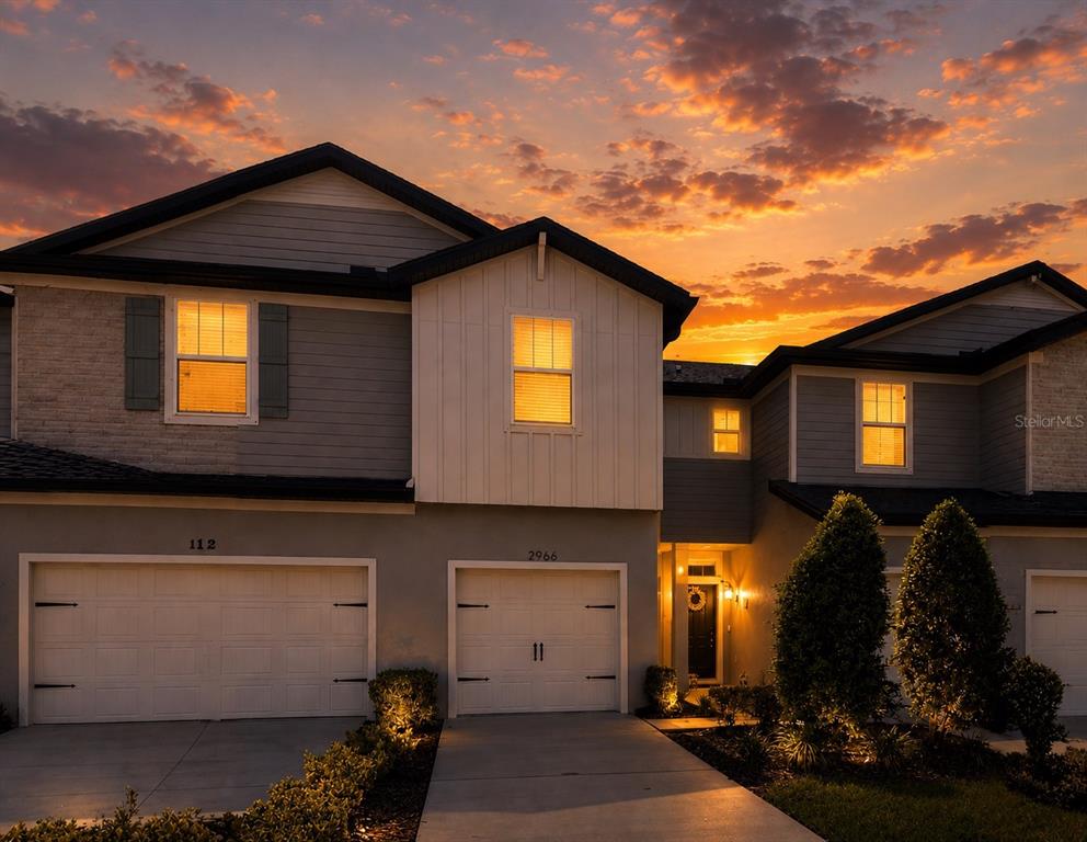 A two-story suburban house exterior with two garages at sunset — 2966 DEER PINE TRAIL, LAND O LAKES, FL