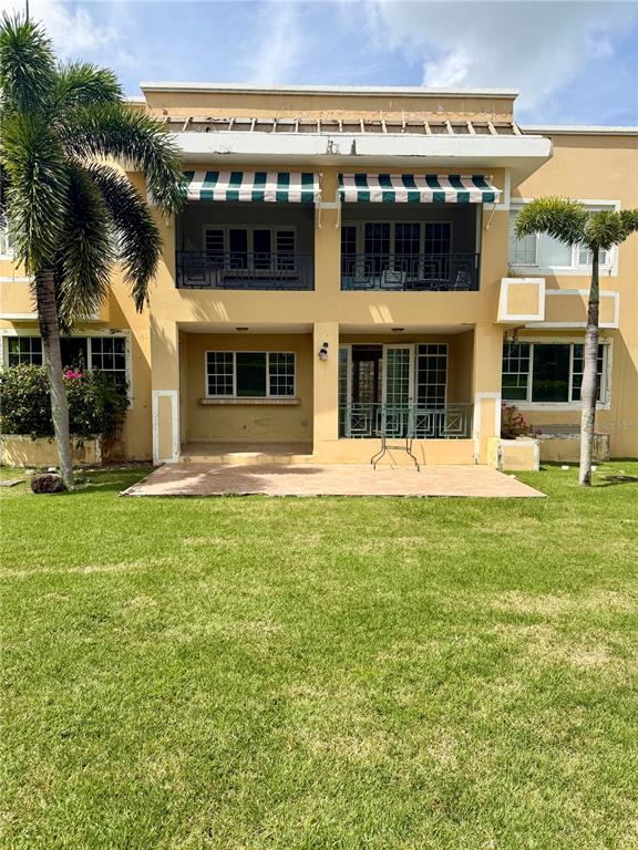 A two-story building features a ground-level patio and a second-floor balcony with striped awnings — 968 COSTA DORADA UNIT 101, RIO GRANDE, PR