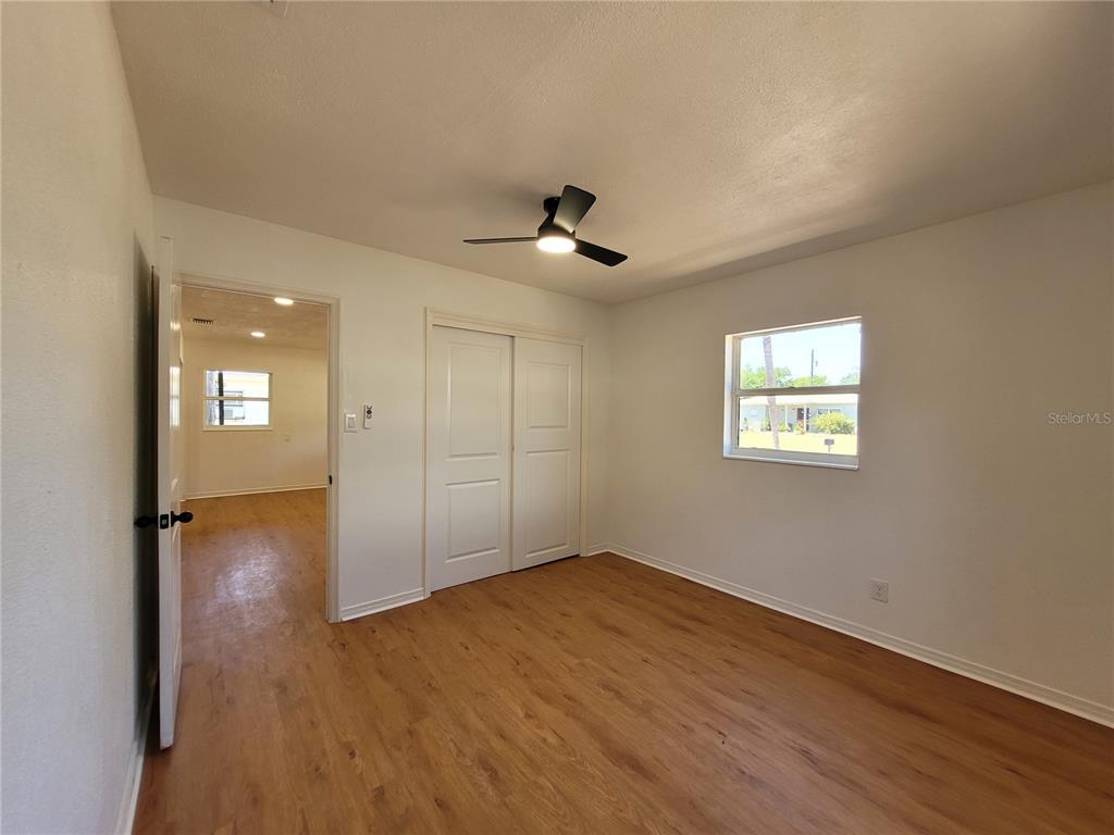 A bedroom with light wood-look flooring, white walls, a ceiling fan, and a sliding closet — 6023 FLORA TERRACE, APOLLO BEACH, FL