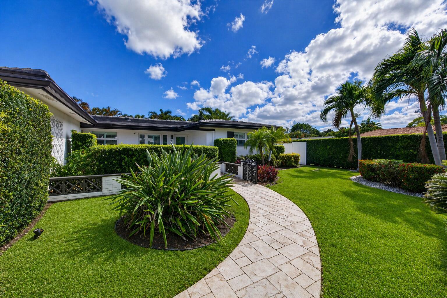 A stone walkway leads to the entrance of a white house surrounded by manicured hedges — 850 W Camino Real, Boca Raton FL 33486, BOCA RATON, FL