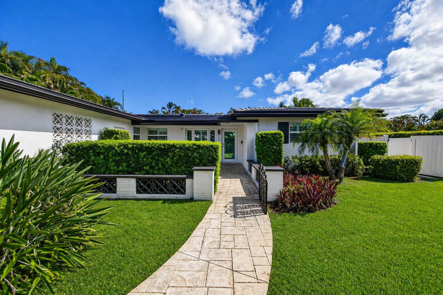 A stone walkway leads to the front entrance of a white house with manicured hedges — 850 W Camino Real, Boca Raton FL 33486, BOCA RATON, FL