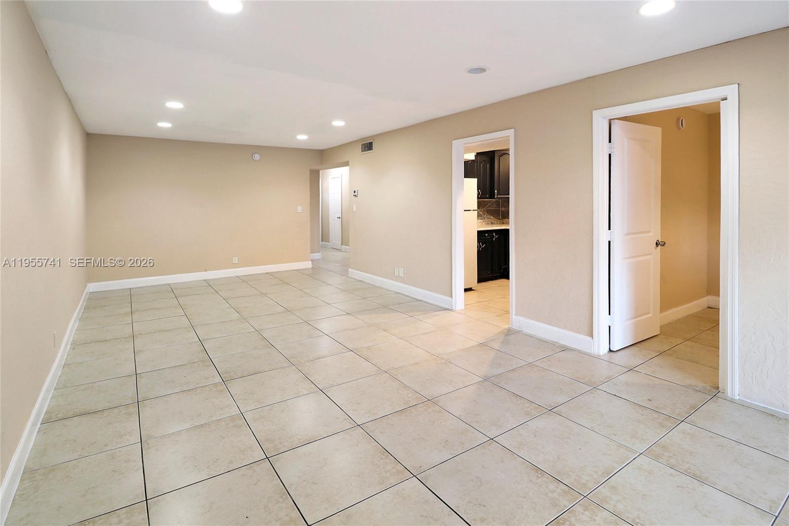 An empty room with beige walls, tile flooring, recessed lighting, and two doorways — 5975 NW 25th Ct # 213, Sunrise FL 33313, SUNRISE, FL