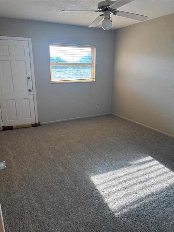 An empty bedroom features gray carpet, light gray walls, a ceiling fan, and a door — 6645 1ST AVENUE N UNIT 307, ST PETERSBURG, FL