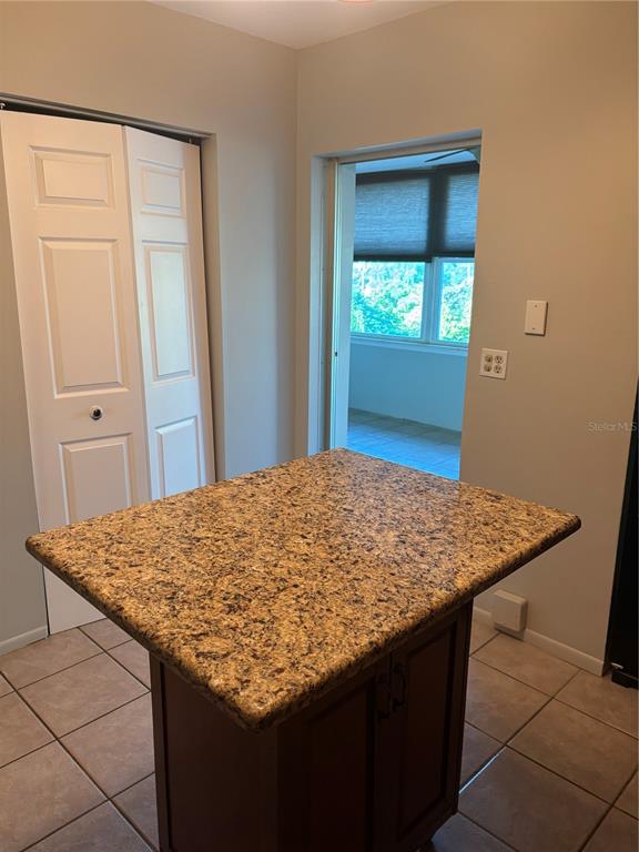 A kitchen island with a granite countertop sits in a room with tile flooring — 6645 1ST AVENUE N UNIT 307, ST PETERSBURG, FL