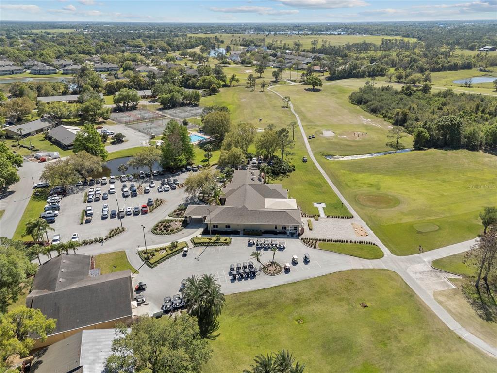 An aerial view shows a clubhouse building surrounded by a parking lot and golf course — 4 ENCLAVE DRIVE, WINTER HAVEN, FL