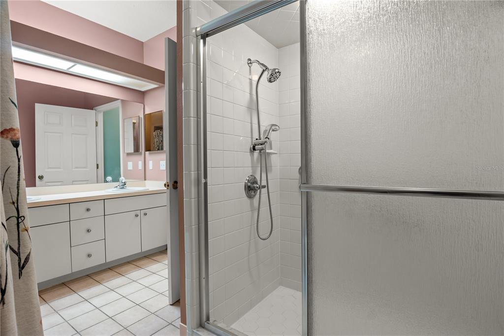 A bathroom features a tiled walk-in shower with a glass door and a white vanity — 4 ENCLAVE DRIVE, WINTER HAVEN, FL