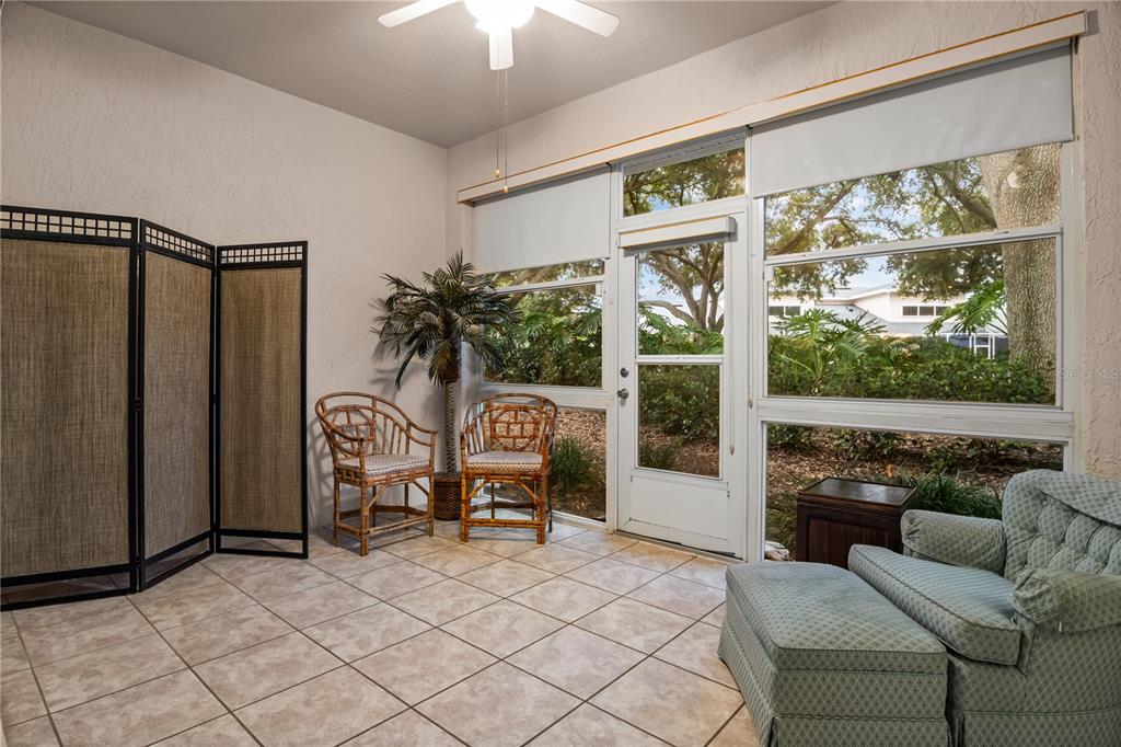 A sunroom features tile flooring, a ceiling fan, wicker chairs, and a glass door — 4 ENCLAVE DRIVE, WINTER HAVEN, FL