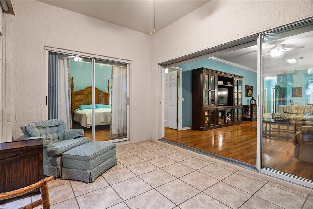 A tiled sunroom features sliding glass doors opening into a bedroom and a living area — 4 ENCLAVE DRIVE, WINTER HAVEN, FL