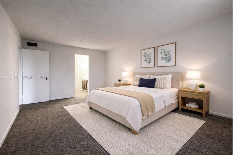 A bedroom features a bed with neutral bedding, two nightstands, and framed botanical wall art — 492 NW 165th St Rd # 611, Miami FL 33169, MIAMI, FL