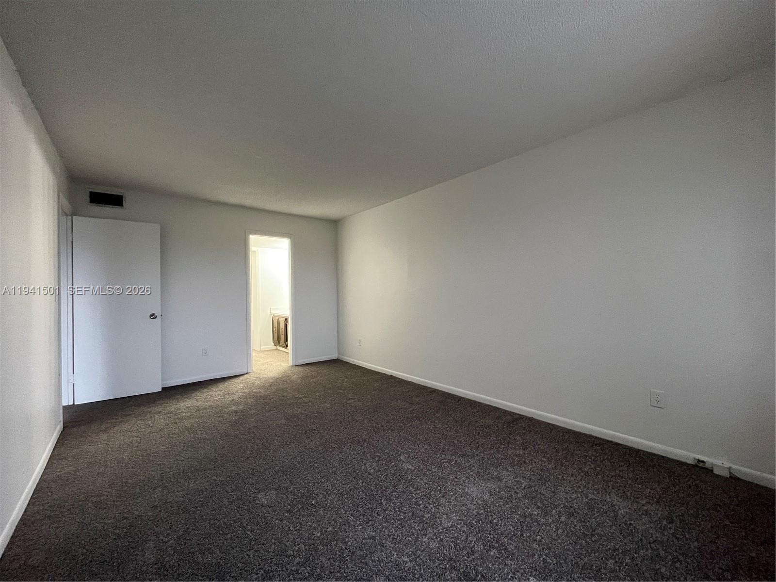 An empty room features gray carpeting, white walls, a closed door, and an open doorway — 492 NW 165th St Rd # 611, Miami FL 33169, MIAMI, FL