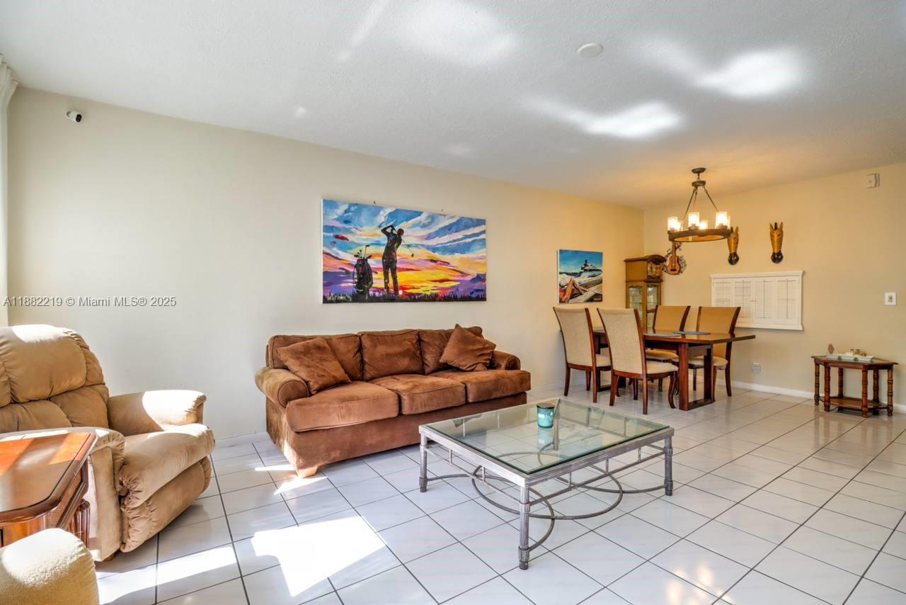 A living and dining area features tile flooring, a brown sofa, and a glass coffee table — 850 NE 12th Ave # 210, Hallandale Beach FL 33009, HALLANDALE BEACH, FL