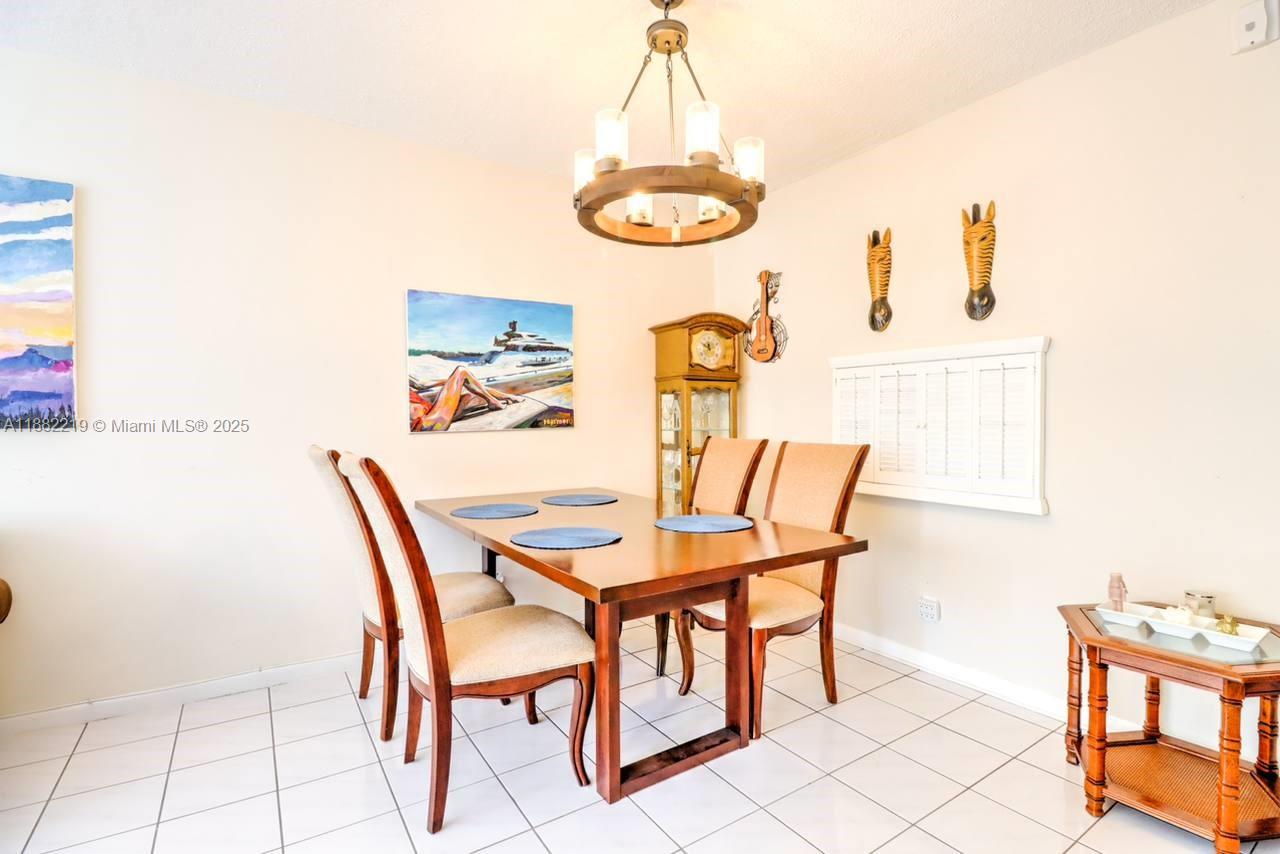 A dining room features a wooden table, four chairs, a chandelier, and wall art — 850 NE 12th Ave # 210, Hallandale Beach FL 33009, HALLANDALE BEACH, FL