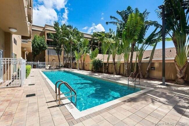 A rectangular swimming pool is surrounded by a paved patio and tropical landscaping — 2665 SW 37th Ave # 611, Miami FL 33133, MIAMI, FL