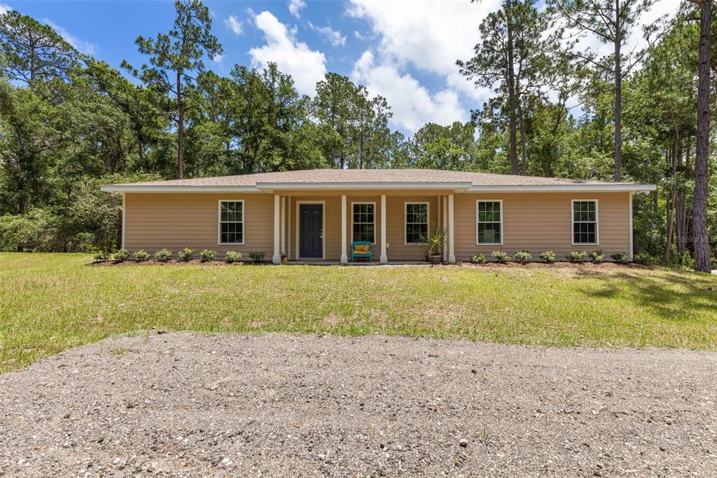 A single-story house with tan siding and a covered front porch sits on a grassy lot — 3296 N OLD DIXIE HIGHWAY, BUNNELL, FL