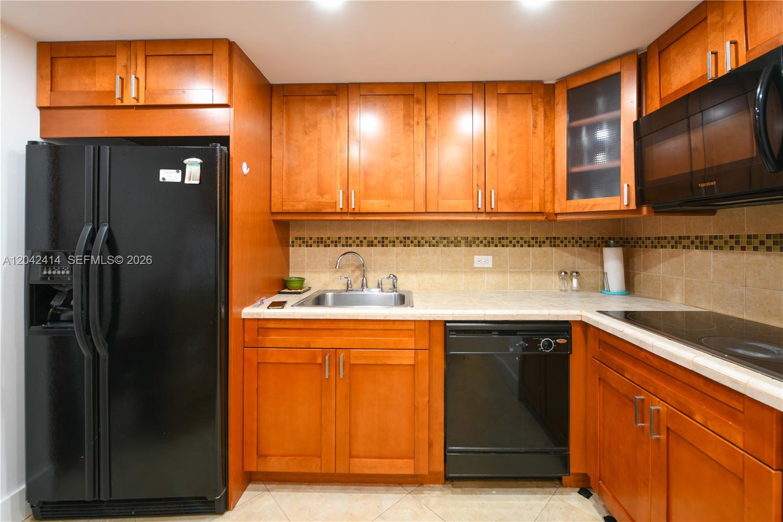 A kitchen features wood cabinets, black appliances, a tiled backsplash, and a stainless steel sink — 801 Brickell Bay Dr # 1462, Miami FL 33131, MIAMI, FL