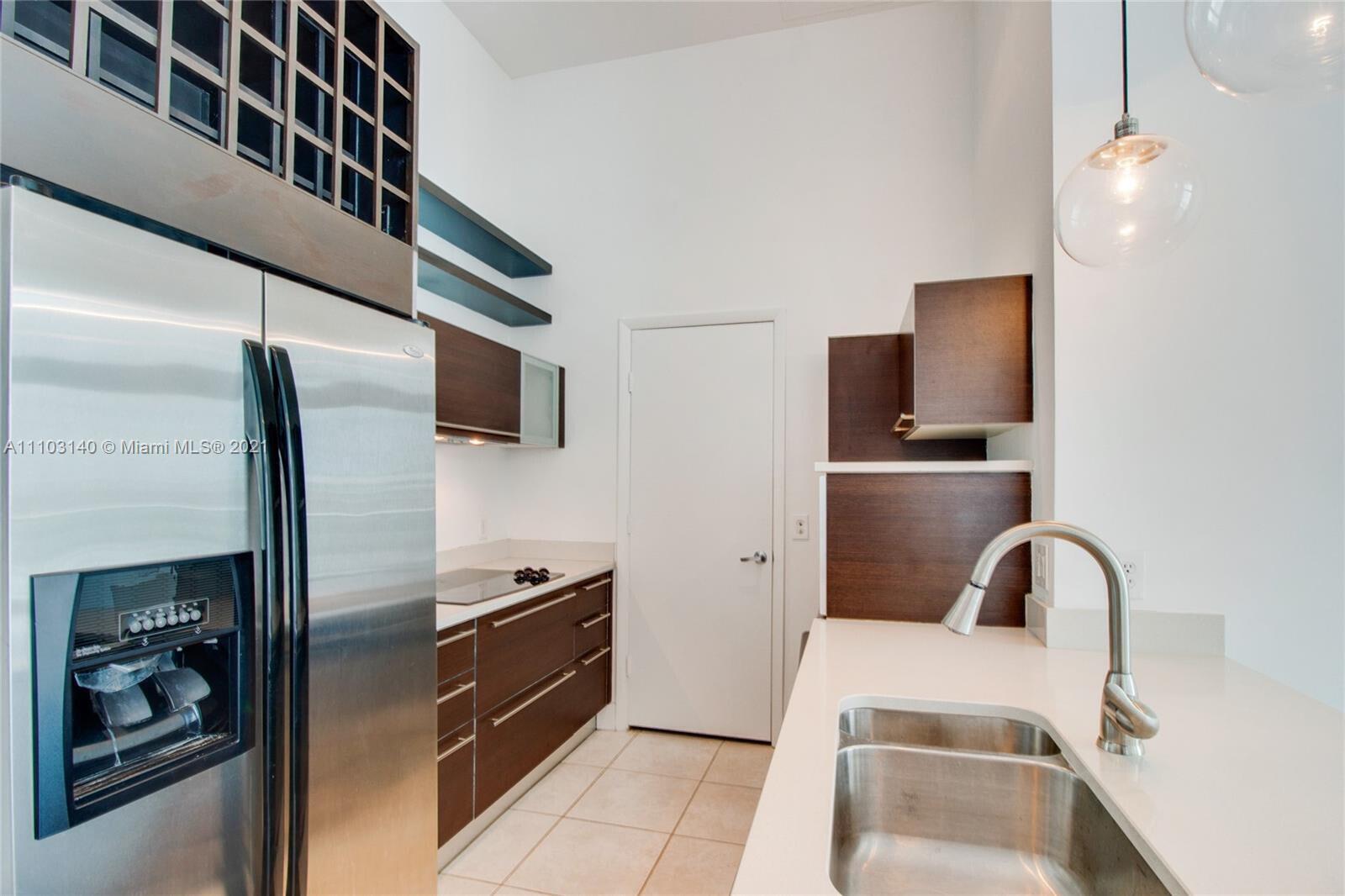 A modern kitchen features stainless steel appliances, dark wood cabinetry, and white countertops — 1900 N Bayshore Drive # 912, Miami FL 33132, MIAMI, FL