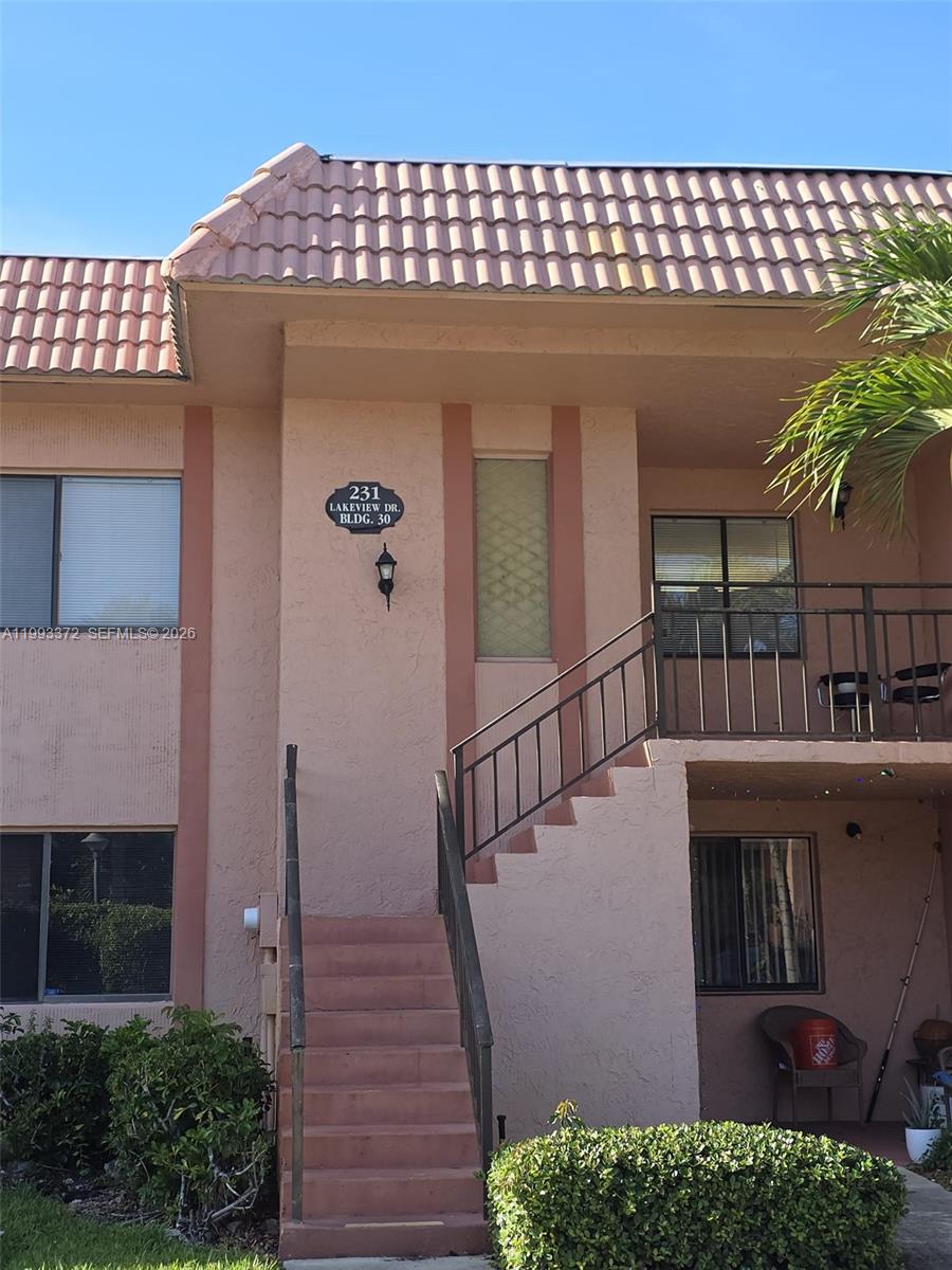 A two-story stucco building features a staircase leading to an upper-level balcony — 231 Lakeview Dr # 204, Weston FL 33326, WESTON, FL