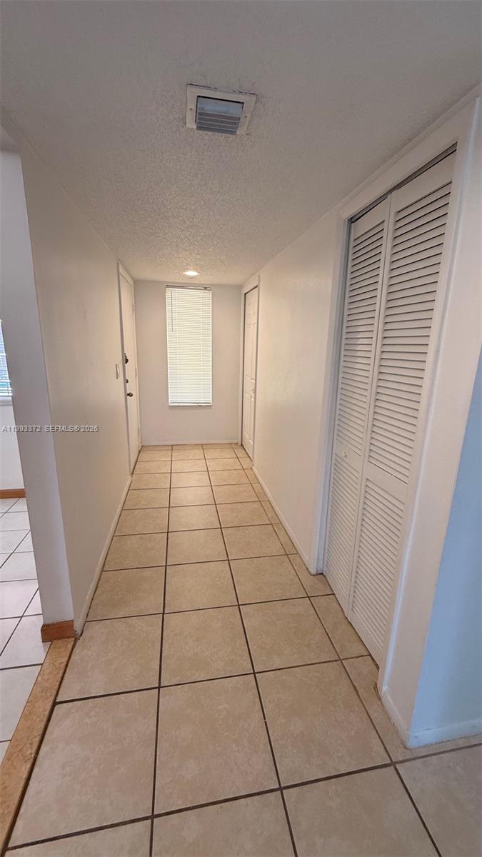A hallway features beige tile flooring, white walls, and a louvered closet door — 231 Lakeview Dr # 204, Weston FL 33326, WESTON, FL