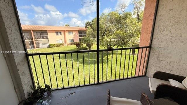 A screened-in balcony overlooks a grassy lawn and a multi-story apartment building — 231 Lakeview Dr # 204, Weston FL 33326, WESTON, FL