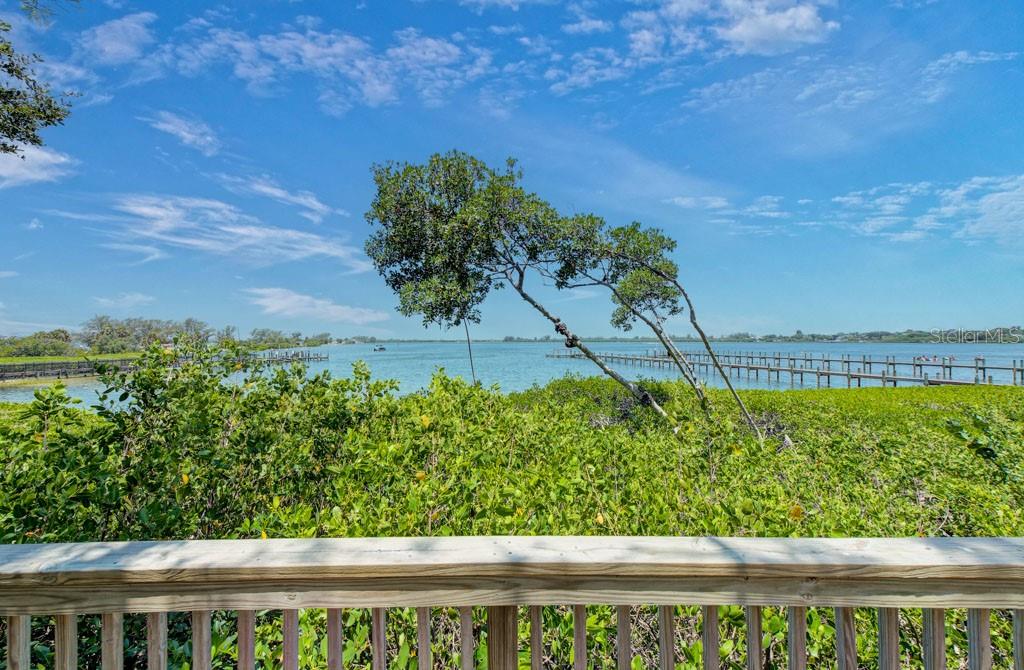 A view of a bay and a wooden dock from a wooden deck railing — 7620 4TH AVENUE W UNIT 7620, BRADENTON, FL