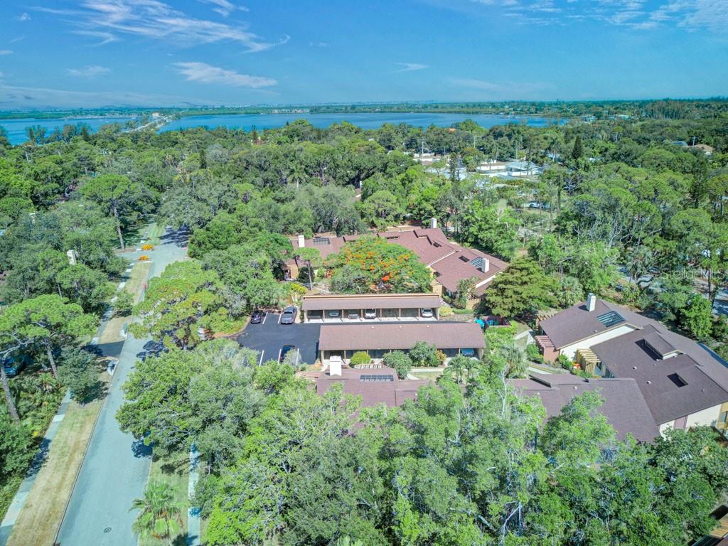 An aerial view shows a multi-building residential complex surrounded by dense trees near water — 7620 4TH AVENUE W UNIT 7620, BRADENTON, FL