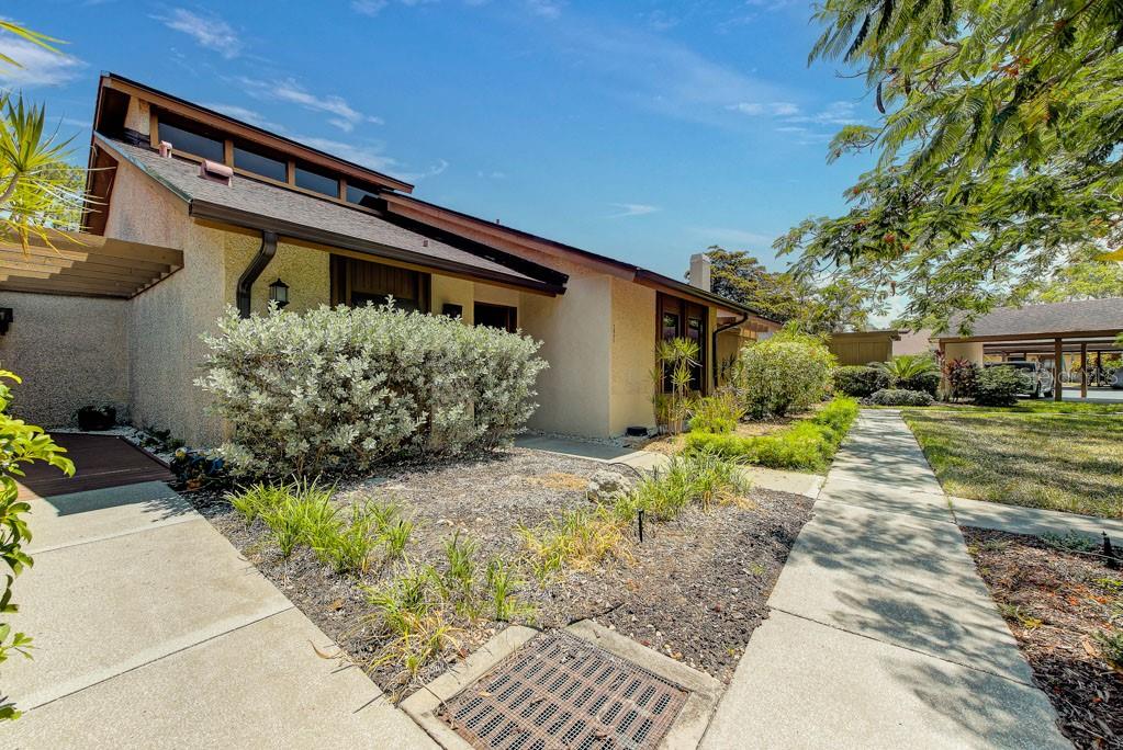 A single-story house with a stucco exterior, a dark shingled roof, and a concrete walkway — 7620 4TH AVENUE W UNIT 7620, BRADENTON, FL