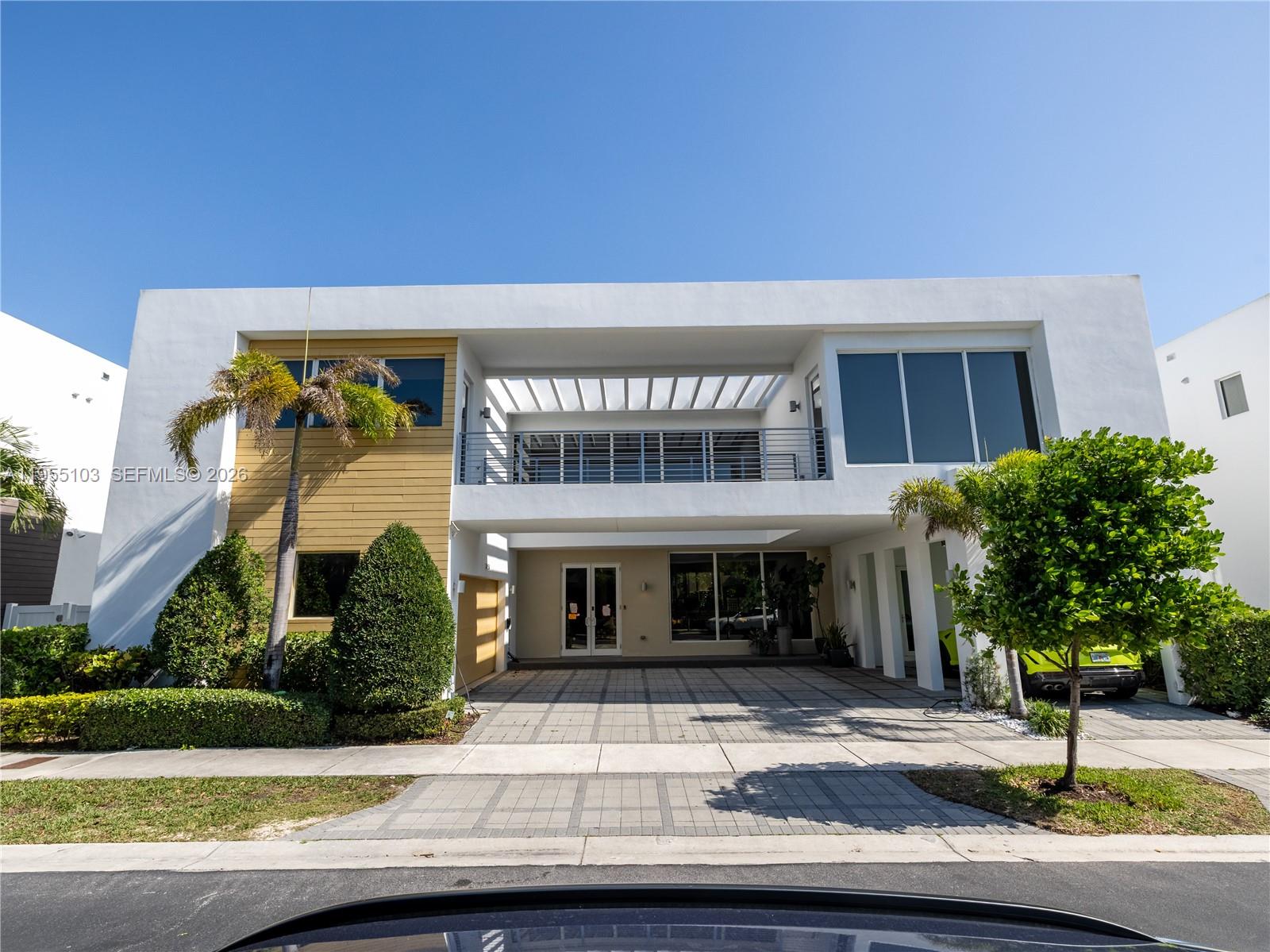 A modern two-story house features a white facade, a recessed balcony, and a paved driveway — 7451 NW 103rd Ct, Doral FL 33178, DORAL, FL