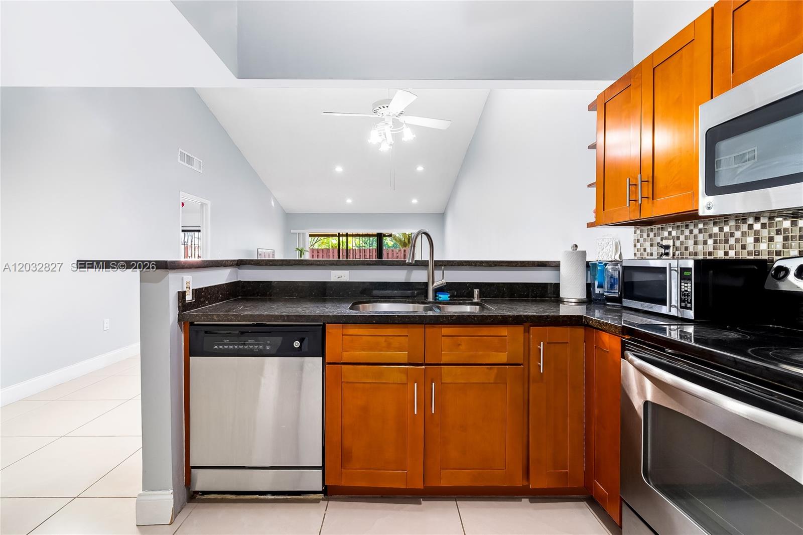 A kitchen features stainless steel appliances, wood cabinets, and a dark countertop with a sink — 505 NE 199th Ln # 2A, Miami FL 33179, MIAMI, FL