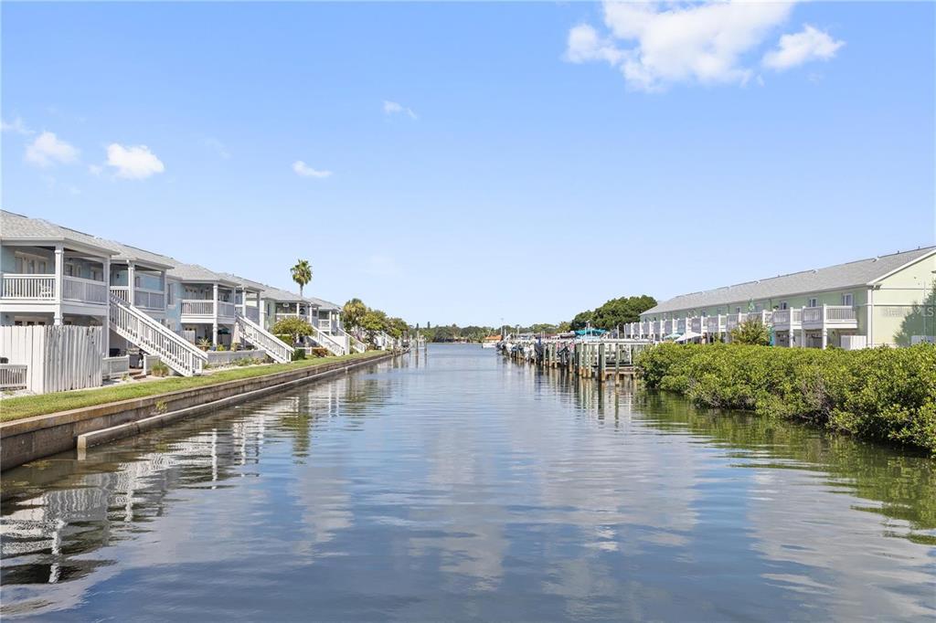 A canal view showing residential townhomes with boat docks on both sides under a blue sky — 5012 STARFISH DRIVE SE UNIT C, ST PETERSBURG, FL