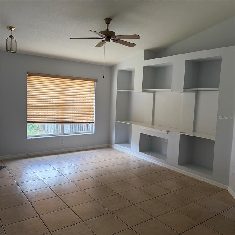 A living room features light-colored tile flooring, a ceiling fan, and a large built-in shelving unit — 2171 EOLA COURT, OVIEDO, FL