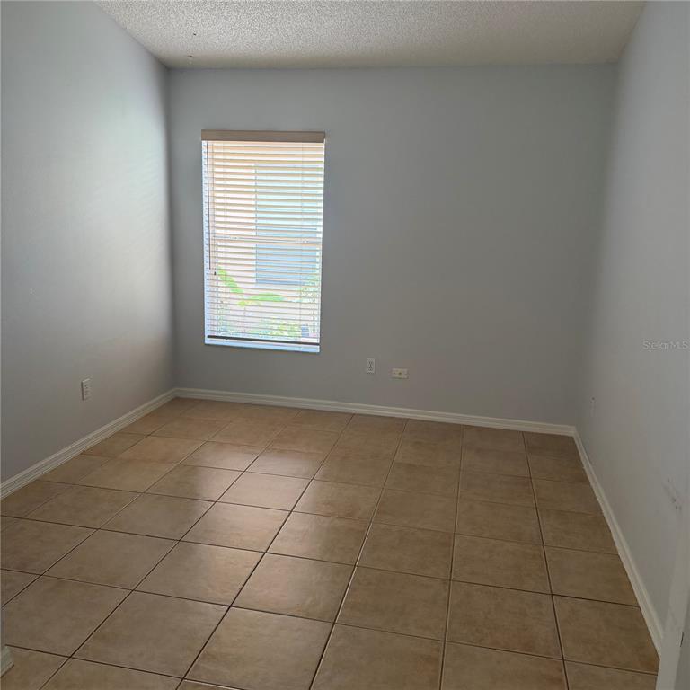 An empty room with light gray walls, beige tile flooring, and a single window — 2171 EOLA COURT, OVIEDO, FL