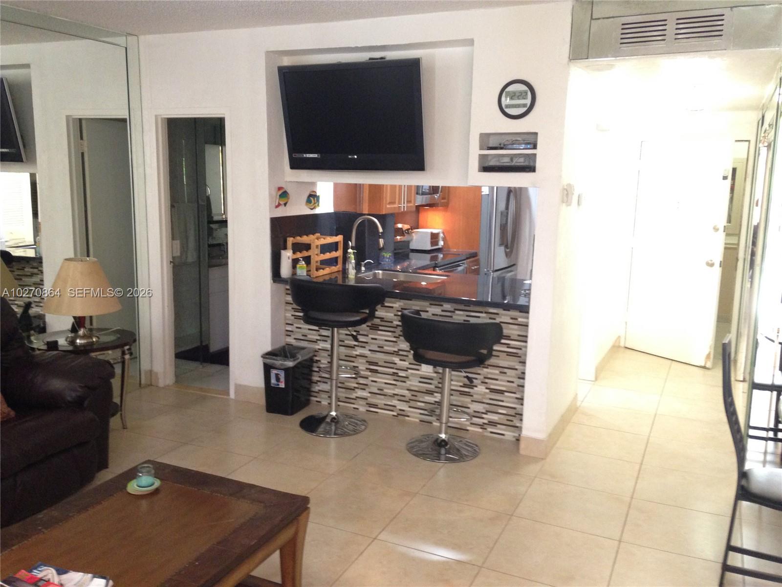 A living room features a kitchen pass-through with a breakfast bar and two stools — 3505 S Ocean Dr # 104, Hollywood FL 33019, HOLLYWOOD, FL