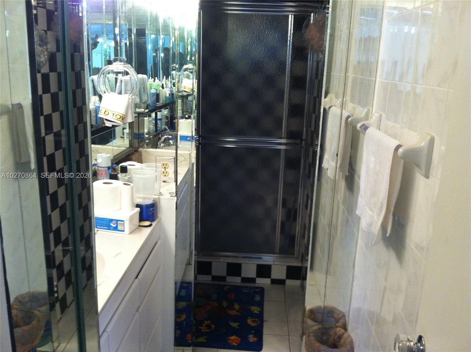 A bathroom features a vanity, a shower with a dark door, and black-and-white checkered tiles — 3505 S Ocean Dr # 104, Hollywood FL 33019, HOLLYWOOD, FL