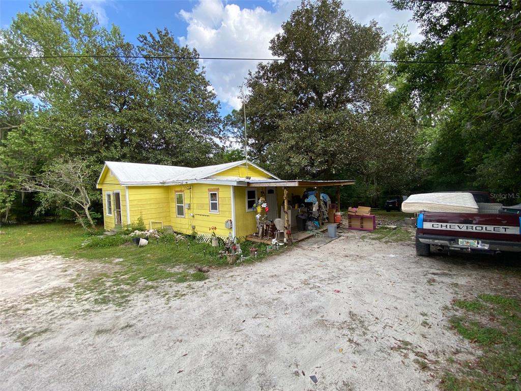A yellow house with a metal roof sits on a dirt lot near a truck — 2714 SE 35TH STREET, GAINESVILLE, FL