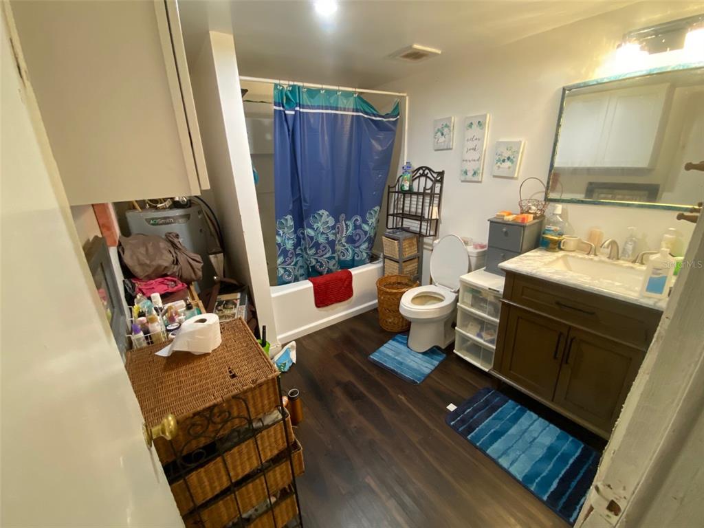 A bathroom features a vanity, toilet, shower-tub combination, and dark wood-look flooring — 2714 SE 35TH STREET, GAINESVILLE, FL