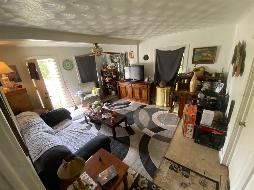 A living room features a patterned area rug, a dark sofa, and a wooden media console — 2714 SE 35TH STREET, GAINESVILLE, FL