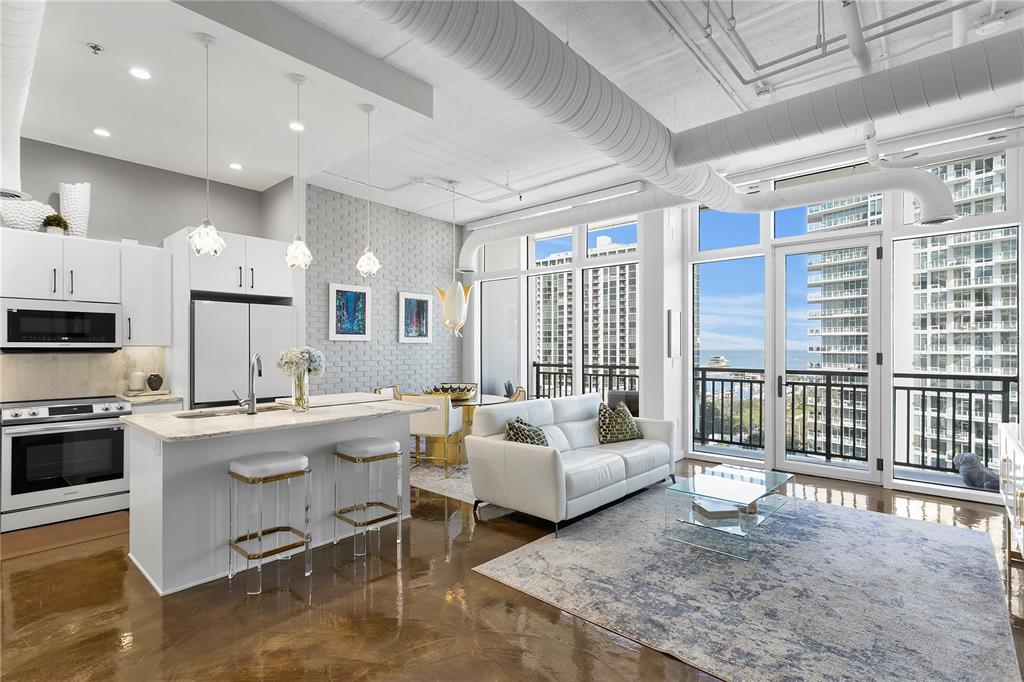 An open-concept condo living area features a white kitchen, dining space, and balcony with views — 175 2ND STREET S UNIT P-08, ST PETERSBURG, FL