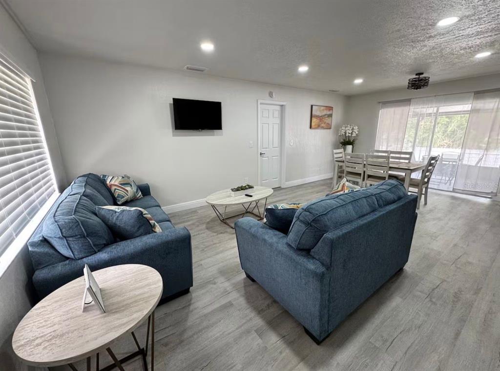 A living room with blue sofas, a coffee table, and an adjacent dining area — 5120 LANDOVER BOULEVARD, SPRING HILL, FL