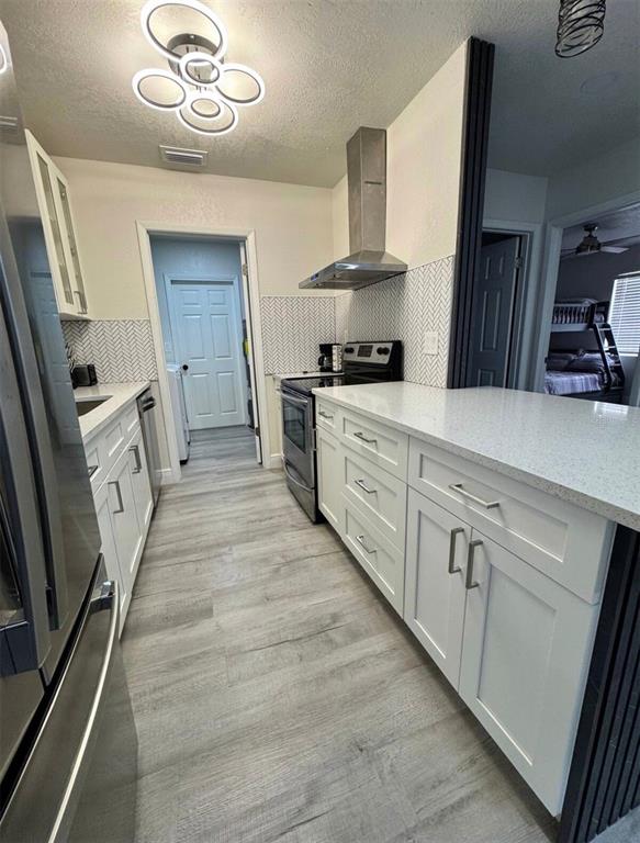 A kitchen features white cabinetry, quartz countertops, a herringbone backsplash, and light wood-look flooring — 5120 LANDOVER BOULEVARD, SPRING HILL, FL