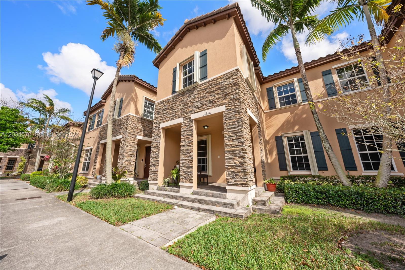 A two-story townhouse exterior features a stone facade, beige stucco walls, and dark shutters — 16958 SW 92nd St # 16958, Miami FL 33196, MIAMI, FL
