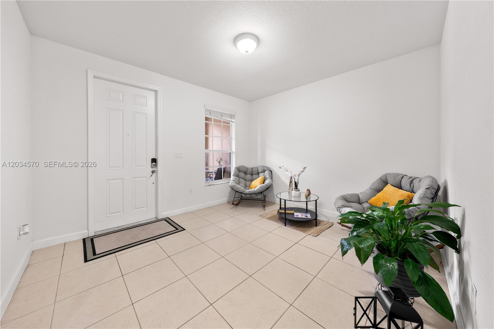 A bright entryway features white walls, tile flooring, two gray chairs, and a small table — 16958 SW 92nd St # 16958, Miami FL 33196, MIAMI, FL