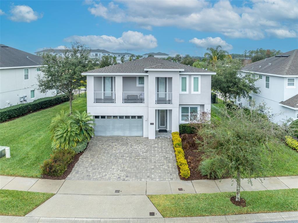 A two-story house with a gray exterior, a paved driveway, and a second-floor balcony — 7744 FAIRFAX DRIVE, KISSIMMEE, FL