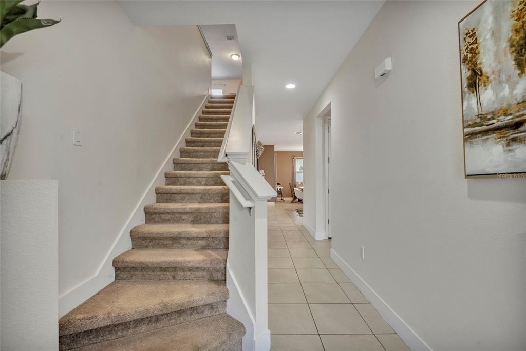 A carpeted staircase leads to an upper level beside a tiled hallway — 7744 FAIRFAX DRIVE, KISSIMMEE, FL