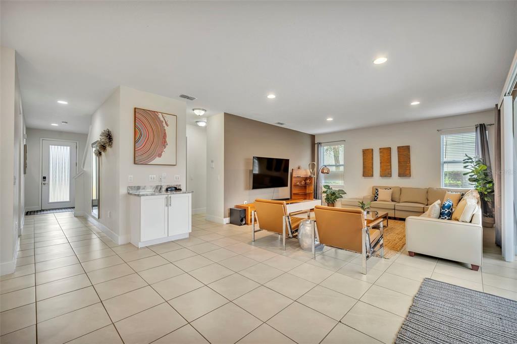 A living room with tile floors, a wall-mounted television, and a beige sectional sofa — 7744 FAIRFAX DRIVE, KISSIMMEE, FL