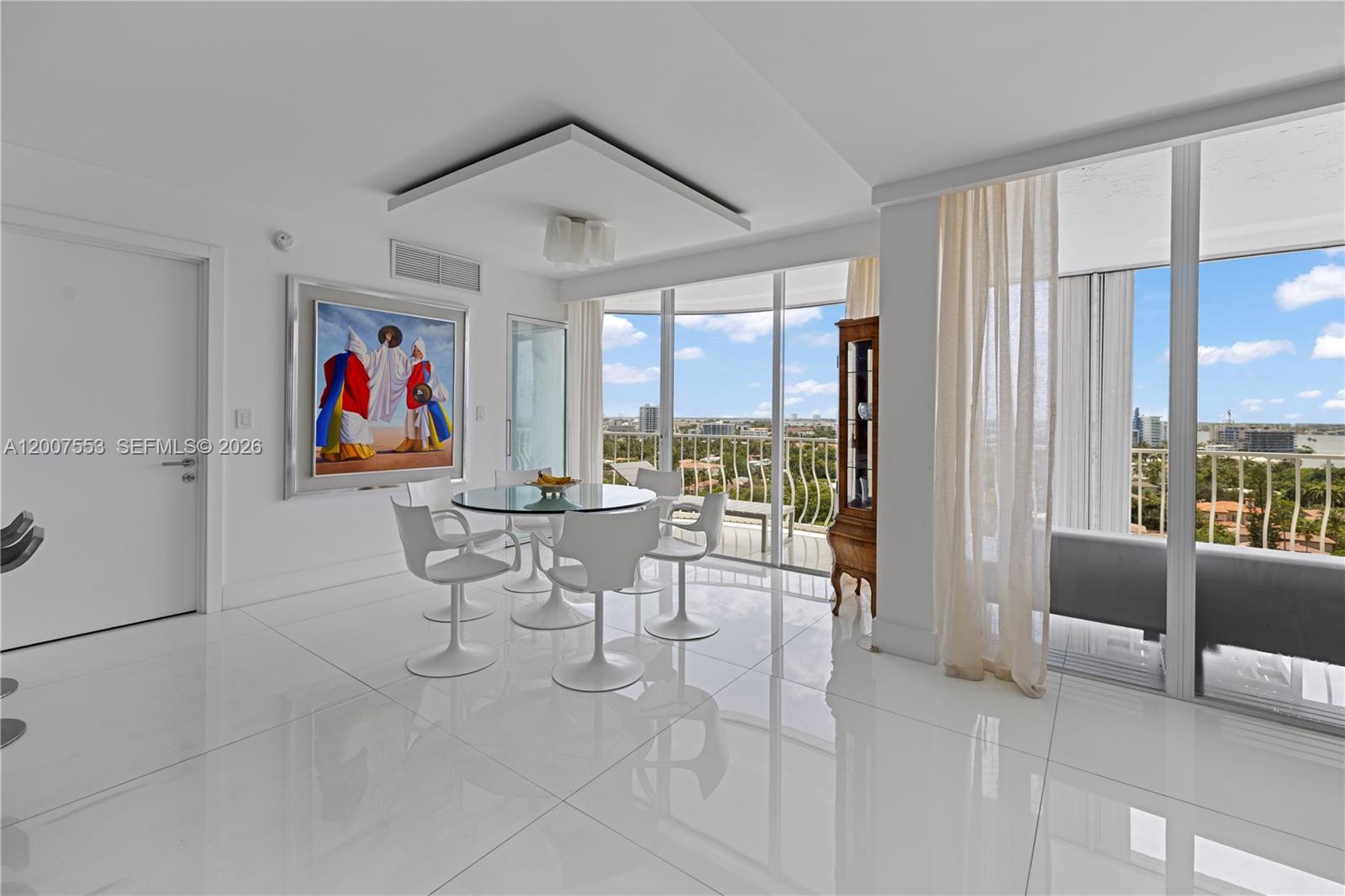 A modern dining room features white tile floors, a glass table, and floor-to-ceiling windows — 10155 Collins Ave # 1210, Bal Harbour FL 33154, BAL HARBOUR, FL