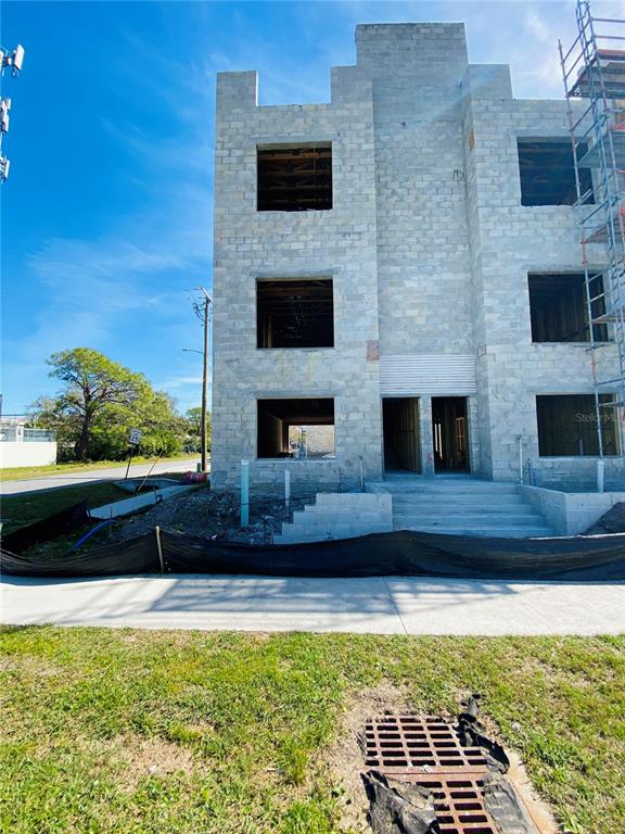 A three-story concrete block building under construction stands behind a black silt fence — 4723 W PRICE AVENUE UNIT 2, TAMPA, FL