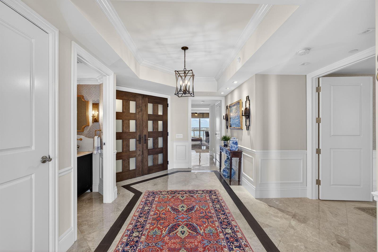 A bright foyer features a patterned area rug, marble flooring, and dark wood double doors — 2700 N Ocean Drive # 1401a, Riviera Beach FL 33404, RIVIERA BEACH, FL