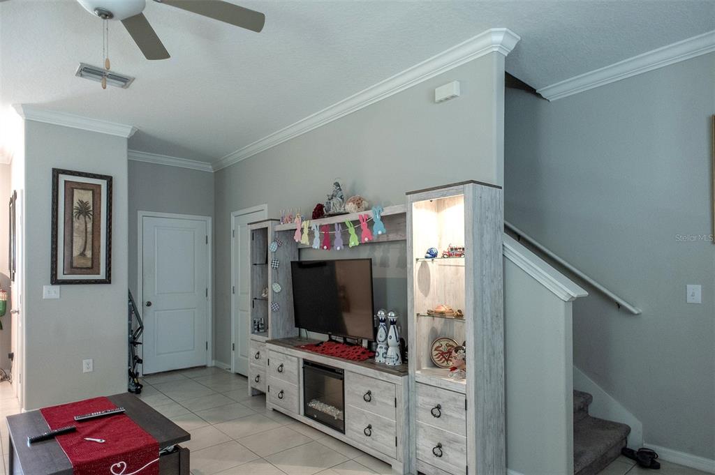 A living room features a white entertainment center, a television, and stairs leading upward — 2160 CERULEAN SKY DRIVE, LUTZ, FL